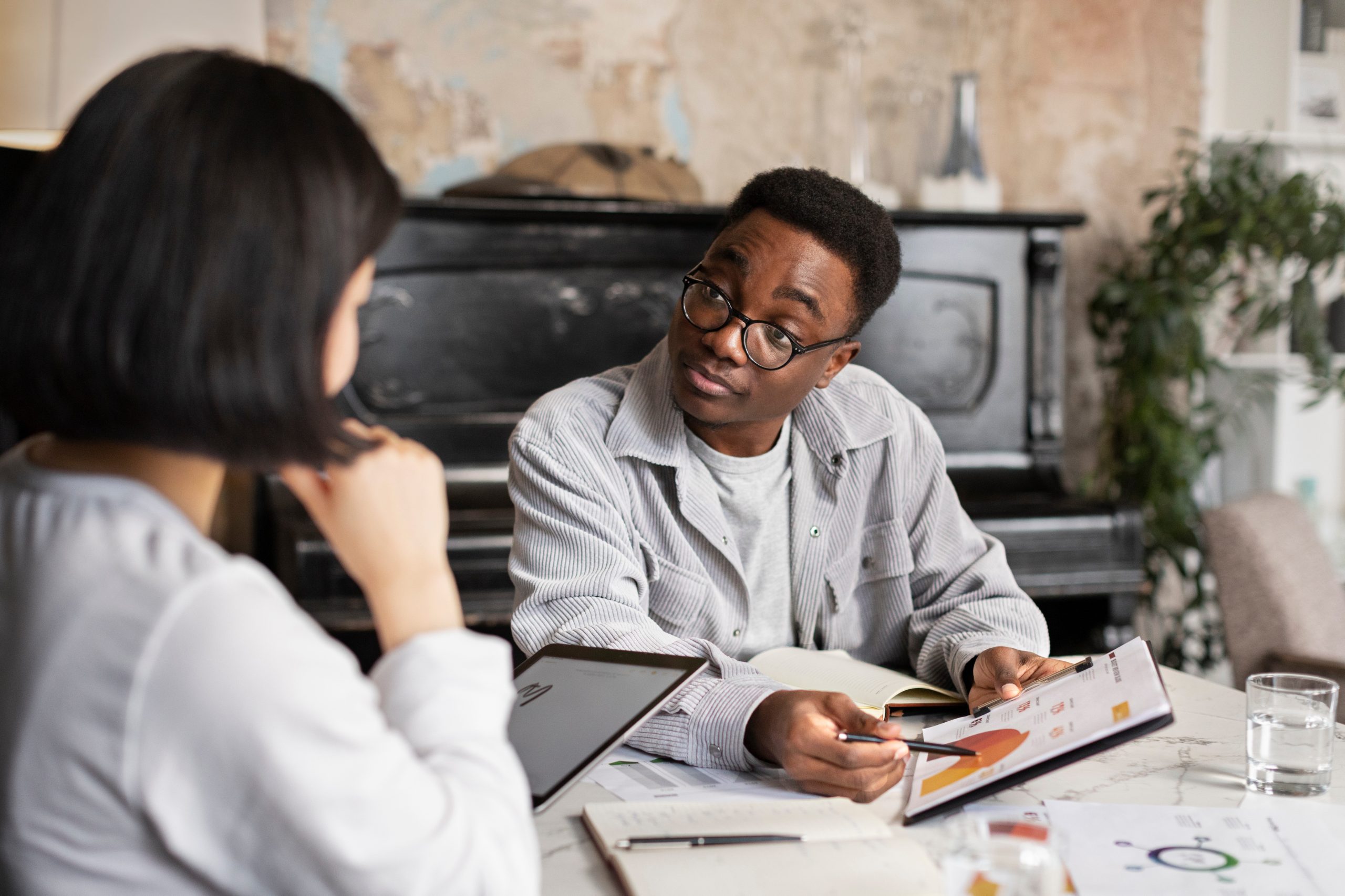Two individuals engaged in a financial planning discussion, with one person pointing at a document featuring graphs and charts, emphasizing the importance of financial literacy and investment strategies for building generational wealth.